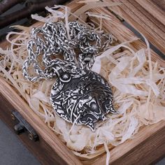 a necklace is in a wooden box on some shredded up paper and chains are around it