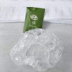 a green bag sitting on top of a bed next to a white towel