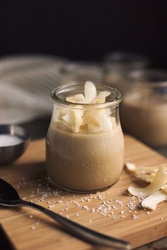 a jar filled with food sitting on top of a wooden cutting board next to spoons