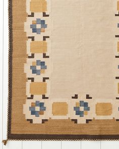 an old rug with blue and yellow squares in the center on a wooden floor next to a white wall