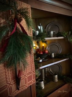 a christmas display with pine branches and other holiday decorations on shelves in a hutch