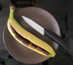 a banana and knife sitting on top of a plate with some chocolate in the middle