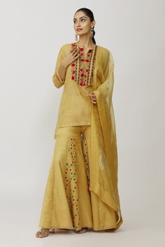 Gold kurta with hand embroidered yoke and sleeves. Comes with bustier, gharara and dupatta.
Components: 4
Pattern: Embroidery
Type Of Work: Floral
Neckline: Kurta: Notched, Bustier: Scoop
Sleeve Type: Kurta: Three quarter, Bustier: Sleeveless
Fabric: Tissue, Cotton Lycra, Voile, Organza
Color: Gold
Other Details: 
Panelled gharara
Approx weight (in gms): 700
Closure: Gharara: Elastic
Occasion: Work - Aza Fashions Cotton Silk Palazzo Set With Gota Work, Festive Cotton Silk Sharara For Navratri, Festive Cotton Silk Lehenga With Dori Work, Transitional Anarkali Sets In Gold, Gold Anarkali Sets For Transitional Season, Transitional Gold Anarkali Sets, Semi-stitched Slub Silk Sets With Dori Work, Cotton Silk Palazzo Set With Resham Embroidery For Festivals, Festive Cotton Silk Palazzo Set With Gota Work