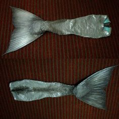 two fish made out of silver foil sitting on top of a red couch next to each other