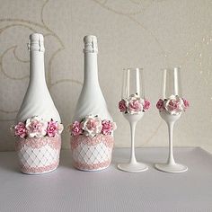 three wine bottles and four glasses with flowers on the bottom one is white, the other has pink roses