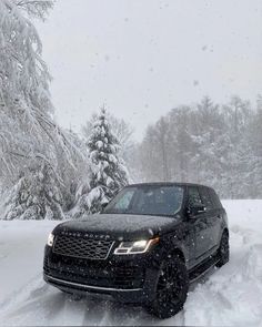 a black range rover driving down a snow covered road