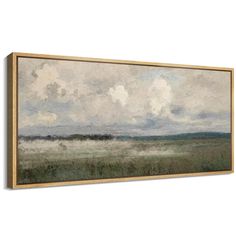 a painting hanging on the wall with clouds above it and grass in the foreground