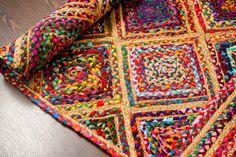 a multicolored crocheted blanket laying on top of a wooden floor