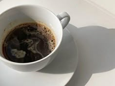 a cup of coffee sitting on top of a white plate