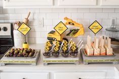 a table topped with lots of desserts and construction themed treats on top of trays