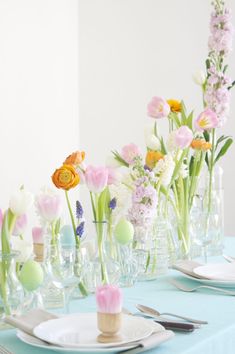 the table is set with flowers in vases and place settings for dinner guests to enjoy