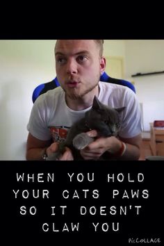 a man holding a cat in his arms with the caption when you hold your cats paws so it doesn't claw you