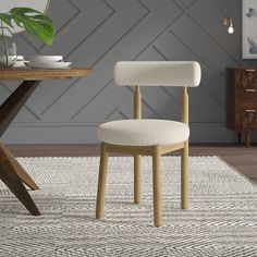 a white chair sitting on top of a rug next to a wooden table with a potted plant