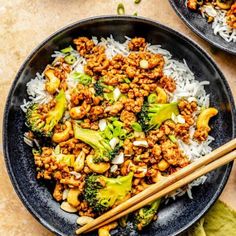 two black plates filled with stir fry and broccoli next to chopsticks