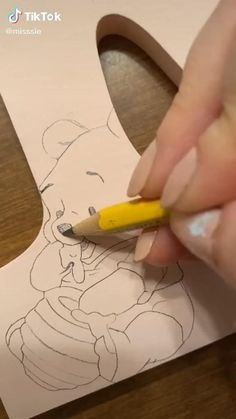 someone is drawing a bear on paper with a pencil