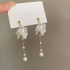 a pair of earrings with pearls hanging from it's ear wires and attached to a card