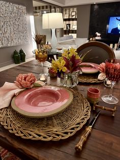 the table is set with pink plates and place settings