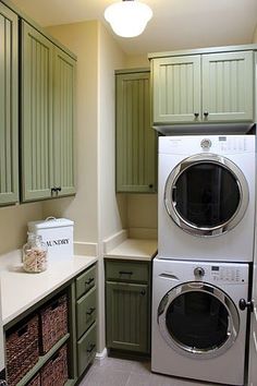 a washer and dryer in a small room with green cabinets on the walls