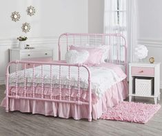 a pink metal bed with ruffled bedspread and pillows