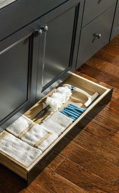 a kitchen drawer is open to show the cleaning supplies in it and on the floor