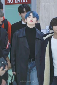 two young men with blue hair walking down the street in front of people wearing headphones