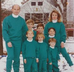 a group of people standing in the snow with one woman and two children wearing green outfits