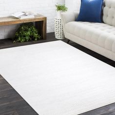 a living room with a white rug on the floor next to a couch and coffee table