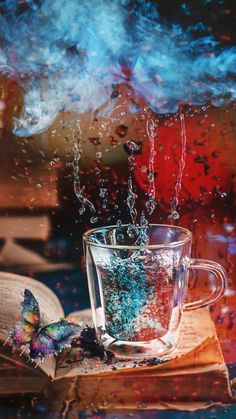 an open book sitting on top of a table next to a glass cup filled with liquid