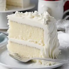 a slice of white cake on a plate with a fork next to the rest of the cake