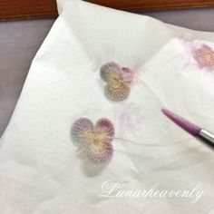 two crocheted hearts are sitting on a piece of white paper next to a brush