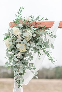 a wedding arch decorated with greenery and white flowers