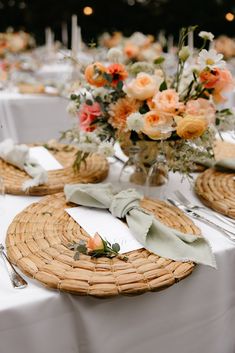 the table is set with white linens and wicker place settings, silverware and flowers