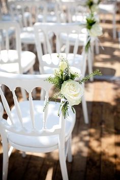 rows of white chairs with flowers on them