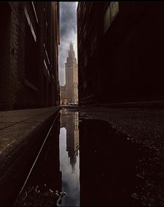 a city street with tall buildings and water in the foreground, on a cloudy day