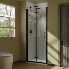 a white toilet sitting next to a shower in a bathroom under a window on top of a hard wood floor