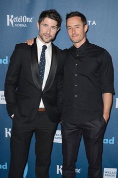 two men standing next to each other on a red carpet