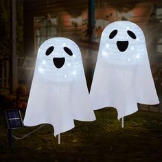 two white ghost shaped lights in the grass