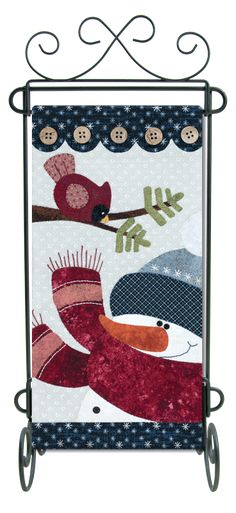 a quilt hanging on the side of a metal rack with birds and snowflakes