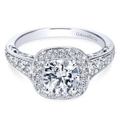 a white gold engagement ring with round diamonds on the shoulders and sides, surrounded by pave