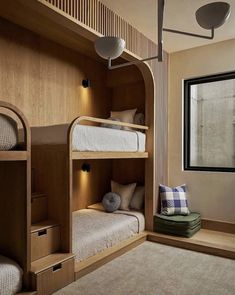 two bunk beds in a room next to a window