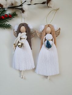 two wooden angel ornaments hanging from a tree