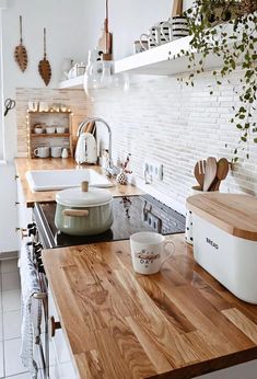 a kitchen with wooden counter tops and white appliances on the wall, along with hanging potted plants