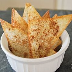 a white bowl filled with baked potato wedges sitting on top of a black counter