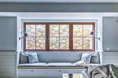 a living room filled with furniture and two windows covered in stone veneers next to a wooden coffee table