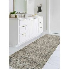 a bathroom with a rug on the floor next to a sink and mirror in it