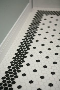 a bathroom floor with black and white hexagonal tiles on the bottom half of it