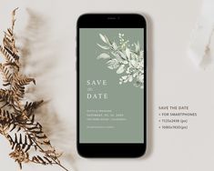 an iphone with save the date cards on it next to some plants and leaves in front of them