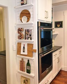 a kitchen with white cabinets and open shelving on the wall next to an oven