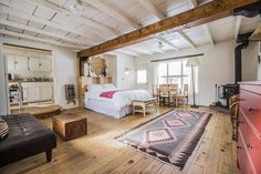 a bedroom with wood floors and white walls, has a large rug on the floor