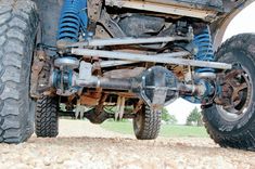 the rear end of a truck with large tires and suspensions on it's sides